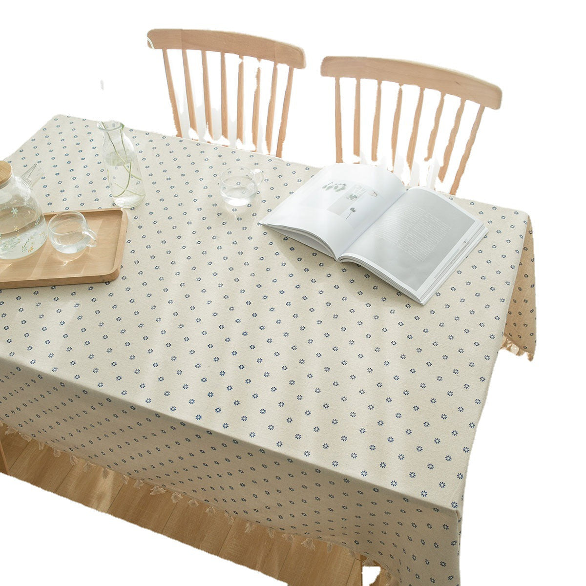 Dining table with a patterned tablecloth, book, and tray on a white background