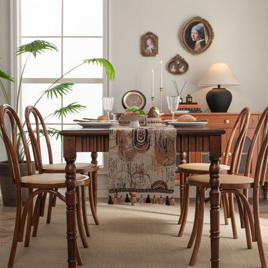 Dining room with wooden table and chairs, decorative tablecloth, and wall art.