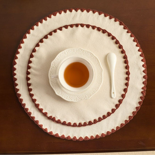 Wooden surface placemat with a beige edge, accompanied by a small cup and a spoon.