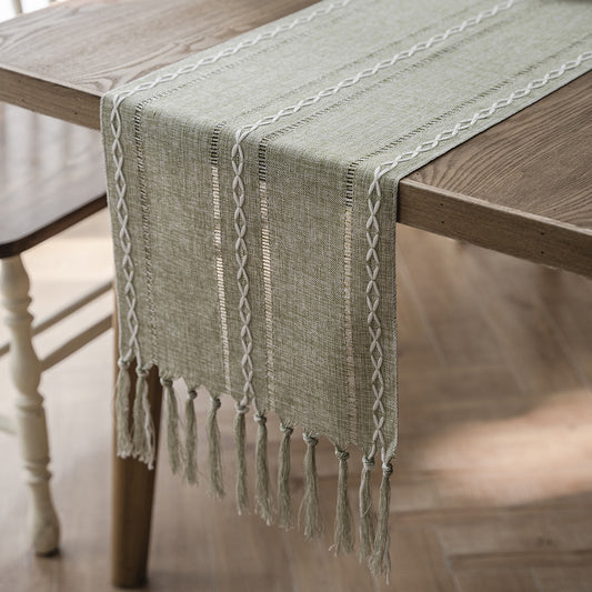 Green woven table runner with fringe on a wooden table