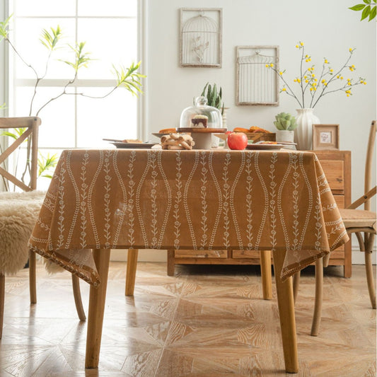 Dining room with a table covered by a patterned tablecloth, surrounded by chairs and decor.