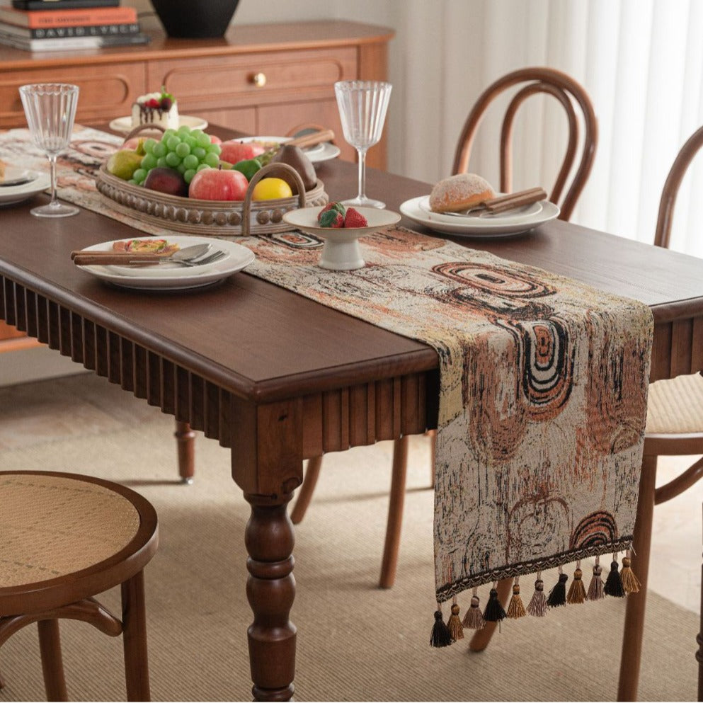 Dining table set with a decorative table runner, plates, and glasses in a home setting.